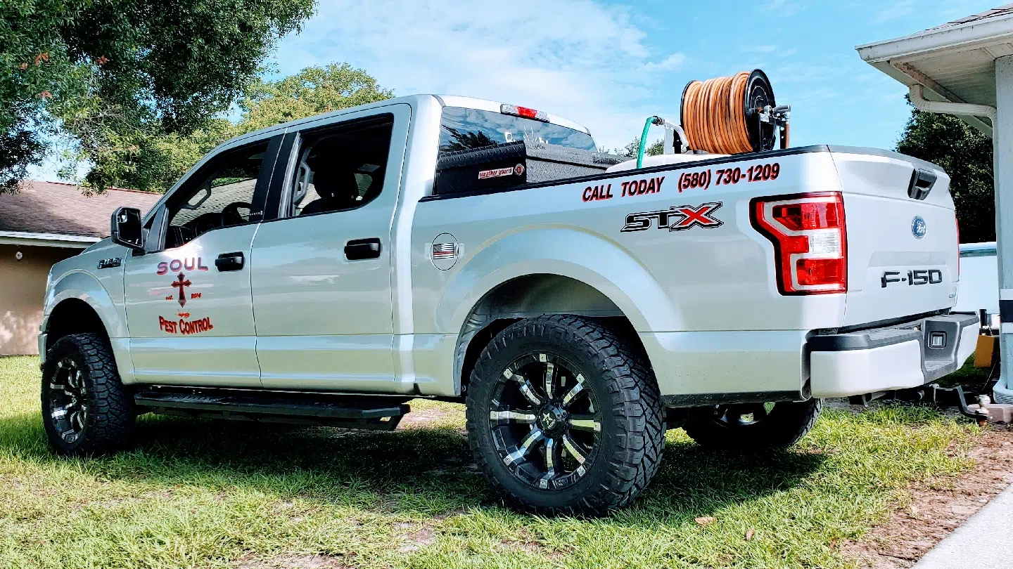 White branded F-150 work truck with hose reel parked on grass — Soul Pest Control, Polk County, FL